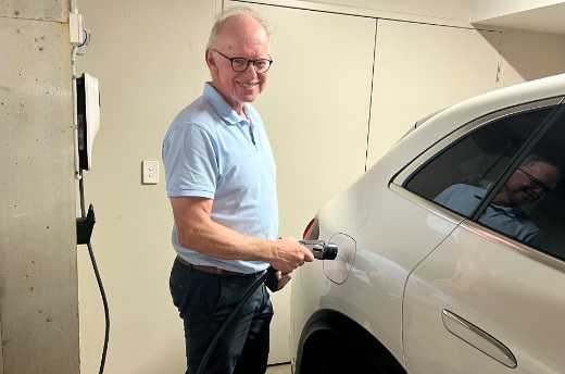 Man charging electric vehicle in car park