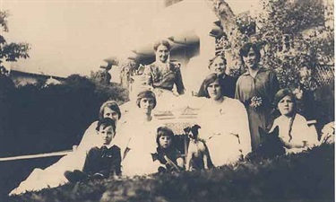 Moulder family, friends and two dogs around the tea table in the garden of St Brigids. Woollahra Libraries Digital Archive, pf002078.