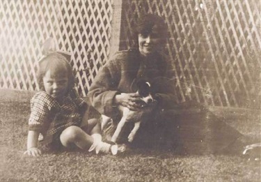 Woman with dog and child sitting on grass at St Brigids, ca. 1913-1916. Woollahra Libraries Digital Archive, pf002457.